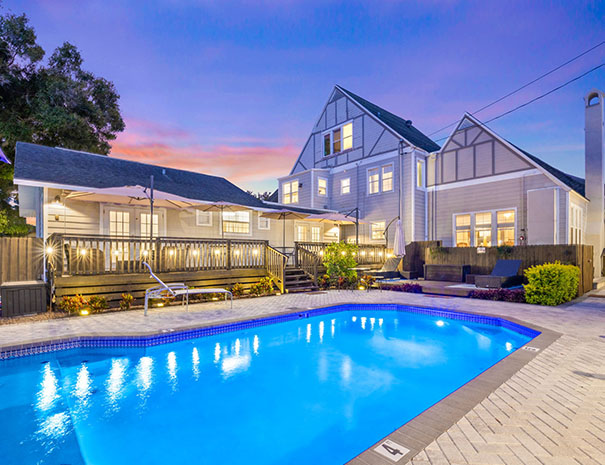 Modern house with illuminated swimming pool at sunset.