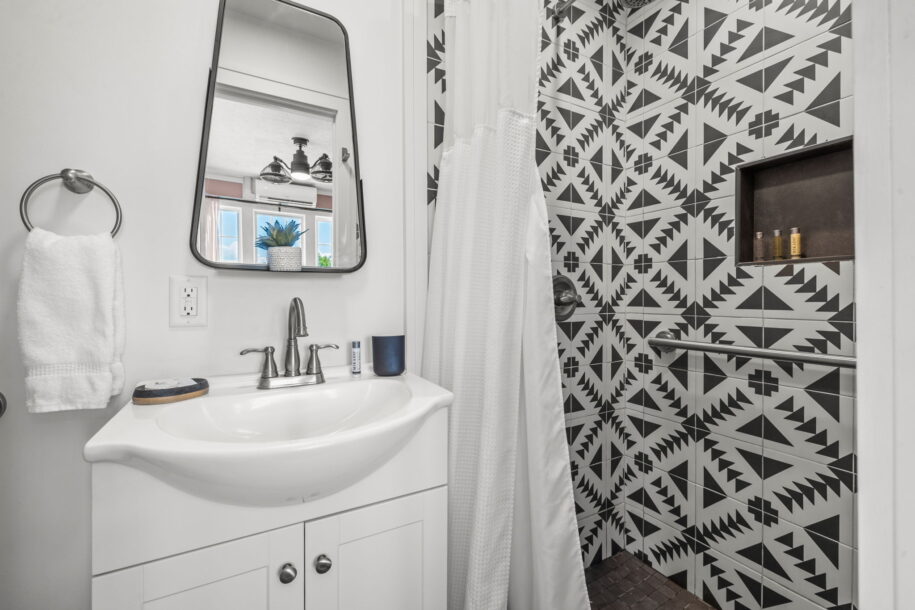 Modern bathroom with geometric black-and-white tiles and a white vanity.