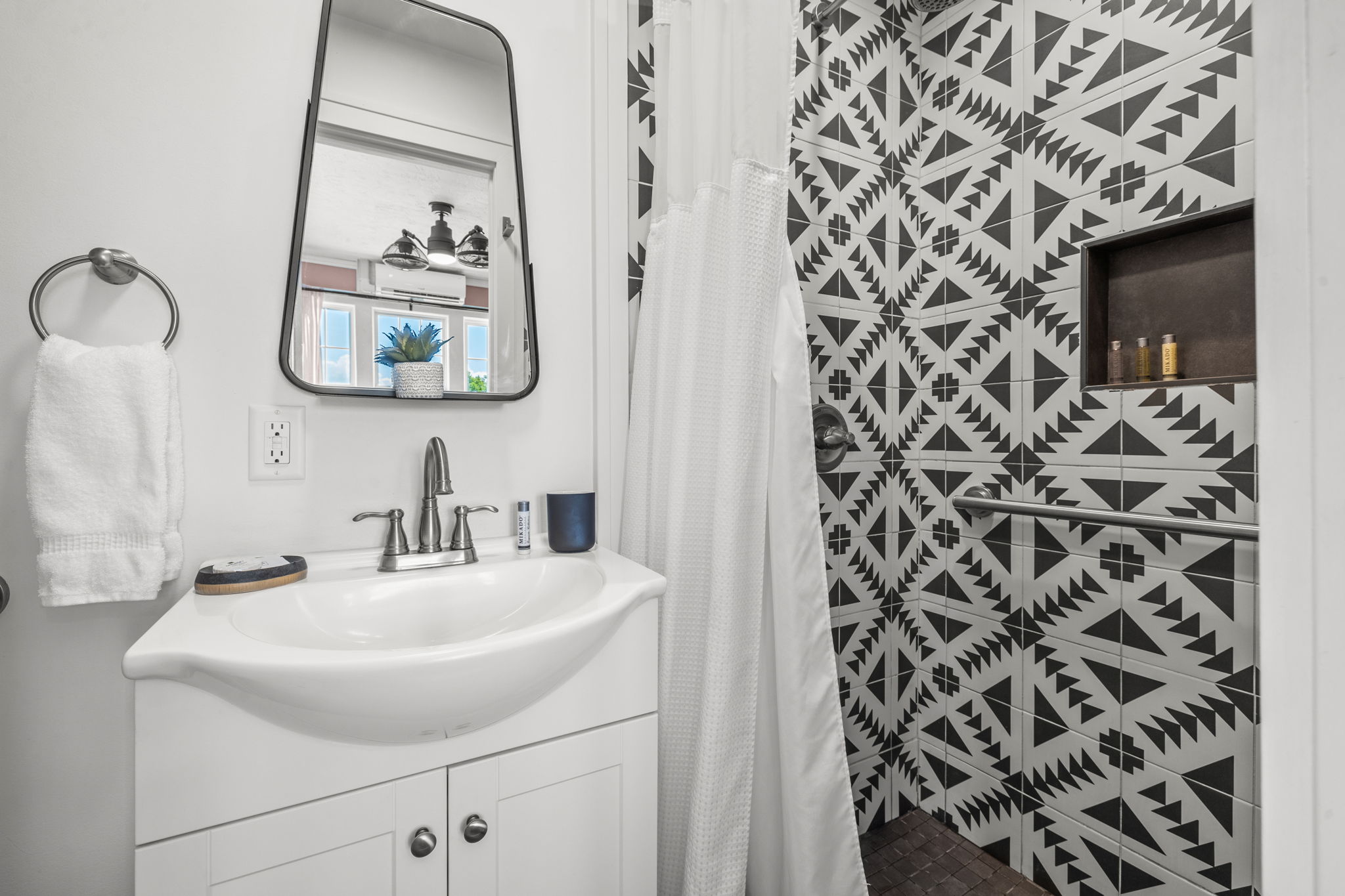 Modern bathroom with geometric black-and-white tiles and a white vanity.