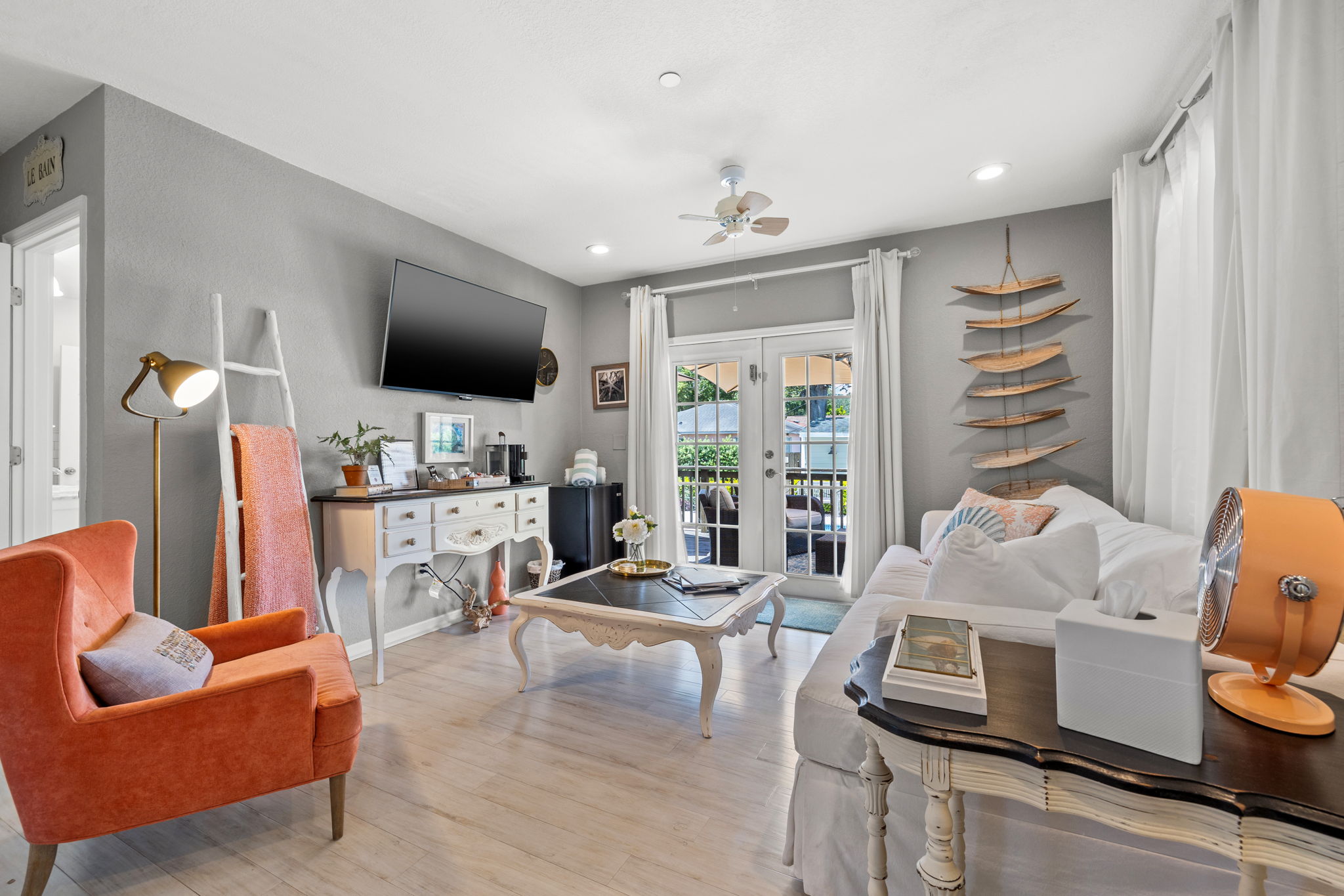 Bright living room with white furniture and balcony doors.